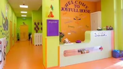 Joyfull House yazılı karşılama bankosu ve renkli giriş holü