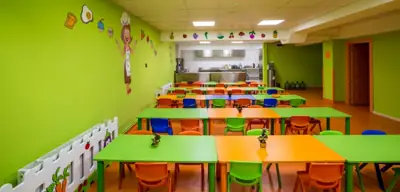 Yemekhane masaları ve arka planda görünen okul mutfağı