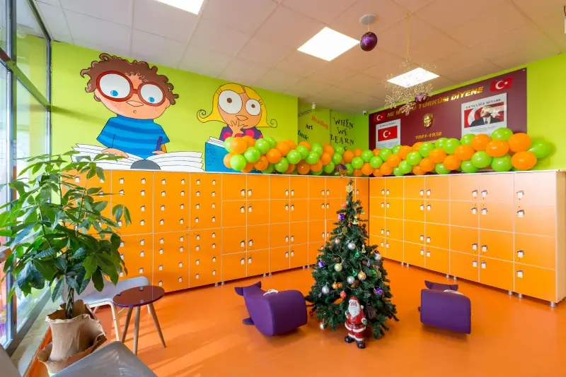 Çocuk dolapları, balon süsü ve oturma pufları bulunan anaokulu ortak alanı