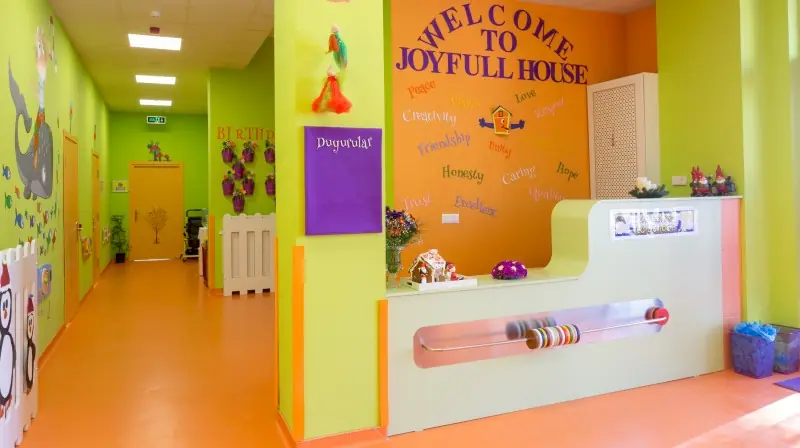 Joyfull House yazılı karşılama bankosu ve renkli giriş holü